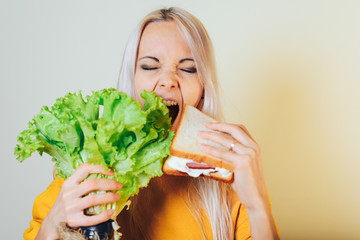 A young girl makes a difficult choice between vegetables or a sandwich with meat. Dieting concept.