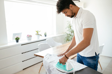 Wall Mural - Young Happy Man Ironing Clothes