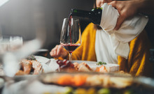 Romantic Young Caucasian Man Pouring Red Wine For His Girlfriend During Dinner Date At Restaurant Enjoying Healthy Food, Romantic Atmosphere, Happy Couple Celebrating Concept