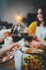 Wall Mural - Vertical image of happy friends cheering with wine glasses at home, family celebrate anniversary enjoying healthy homemade food, Dinner Enjoyment Holidays Friendship Concept