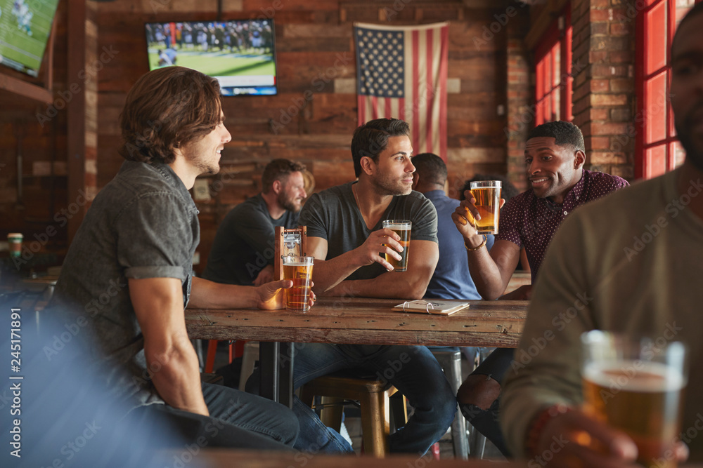 Group Of Male Friends Meeting And Drinking Beer In Sports Bar Together - obrazy, fototapety, plakaty 