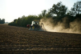 Fototapeta  - Just before sunset, a farmer was still working on a dusty field 