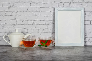 Wall Mural - Tea in a glass cup on a wooden board with a blue and gray background. Close-up. Cup of tea with teapot on a blue gray background.