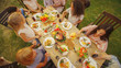 © Gorodenkoff - Big Family Garden Party Celebration, Gathered Together at the Table Relatives and Friends, Young and Elderly are Eating, Drinking, Passing Dishes, Joking and Having Fun. Top Down Shot.