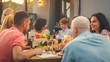 © Gorodenkoff - Big Family Garden Party Celebration, Gathered Together at the Table Relatives and Friends, Young and Elderly are Eating, Drinking, Passing Dishes, Joking and Having Fun. Mother Asks Her Son.