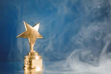Wall Mural - gold star trophy in smoke, blue background