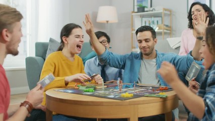 Wall Mural - Diverse Group of Guys and Girls Playing in a Strategic Board Game with Cards and Dice. Cozy Living Room in a Daytime