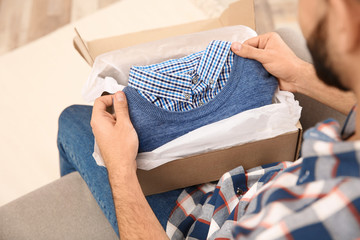 Young man opening parcel at home, closeup