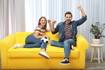 Wall Mural - Couple watching soccer match on TV in living room