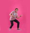 Young man playing air guitar on color background