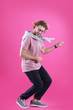 © New Africa - Young man playing air guitar on color background