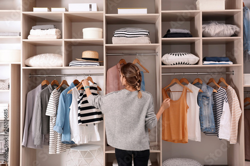 Cuadros en Lienzo Woman choosing outfit from large wardrobe closet with stylish clothes and home s