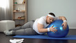 © motortion - Tired unmotivated obese man lying on fitness ball, slimming fitness program