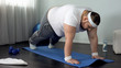© motortion - Fat male trying to do push up exercise at home, weak muscles, lack of motivation