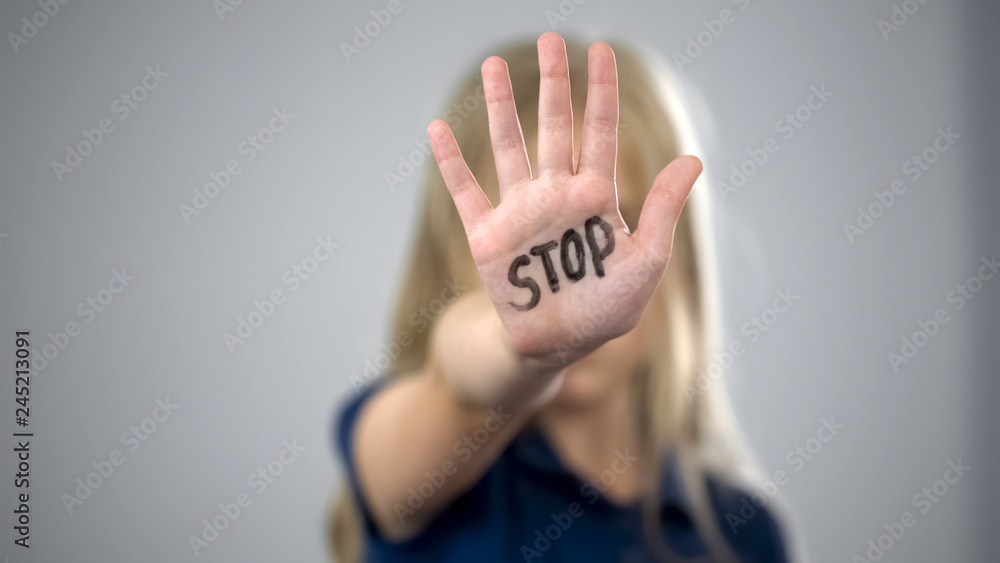 Little girl showing stop sign, child abuse issue, cruelty in family, awareness - obrazy, fototapety, plakaty 