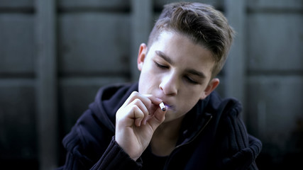 Teen boy smoking cigarette, health problems, lungs cancer risk, social issue