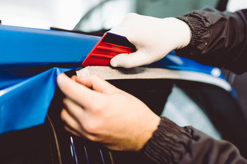 Wall Mural - Car wrapping specialist putting vinyl foil or film on car. Selective focus.