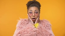Afro-American woman in funny pink coat surprised by interesting news, gossip
