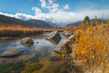 River Cuts Through Plants Near Mountains During Fall