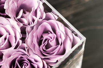 pastel purple hued roses in clear acrylic crystal flower box. square glass gift box. overhead, copys