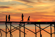 Silhouette Kids Walk On The Wooden Jetty During Sunset At Mantanani Island, Kota Belud, Sabah, Malaysia