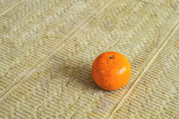 Orange mandarin lying on a soundproof panel made of stone wool.