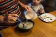 Mother preparing oatmeal breakfast to infant son at the kitchen.