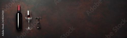 Bottle of wine with wineglass and corkscrew on rusty brown background. Panoramic top view with space for your text © Dz Lab