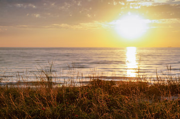 Sunset over the sea. Reflection of sunlight in the sea waves. Red and yellow sky in the rays of the sunset.