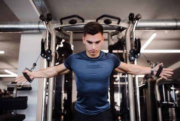 Poster - A young handsome man doing strength workout exercise in gym.