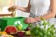 © Photographee.eu - Close-up of a woman putting kiwi peeling into a recycling basket in her kitchen