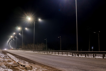 Wall Mural - Fast moving traffic at night. Timelapse. winter season. concept of the road, snow and ice removal, danger and safety of movement, street lighting with energy-saving lamps