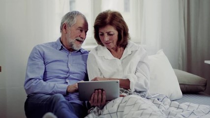 Canvas Print - A senior couple with tablet at home, a husband spending time with his ill wife.