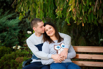 Wall Mural - Couple in love sitting a wooden bench in a park