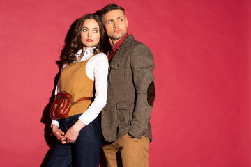 beautiful fashionable couple in formal wear posing on red background with copy space