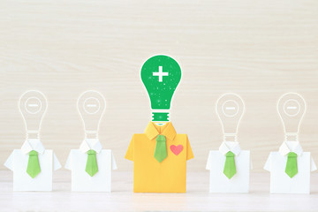 Thinking positive concept, Origami yellow shirt with tie and light bulb with positive and negative thinking on wooder background