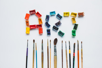 Wall Mural - top view of paintbrushes and art lettering made of paints on white background