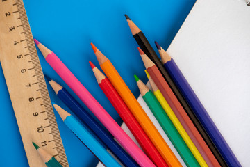 Color pencils, ruler and notepad, on the blue background.