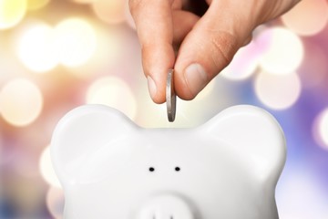 Hand putting coin to piggy bank and coins on white background