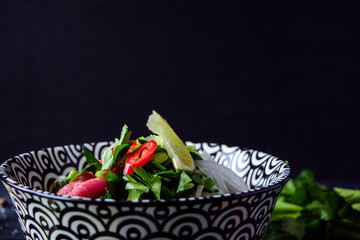 Pho Bo vietnamese soup with noodles, beef, chili pepper, onion,  cilantro and lime on dark black background with copy space on top