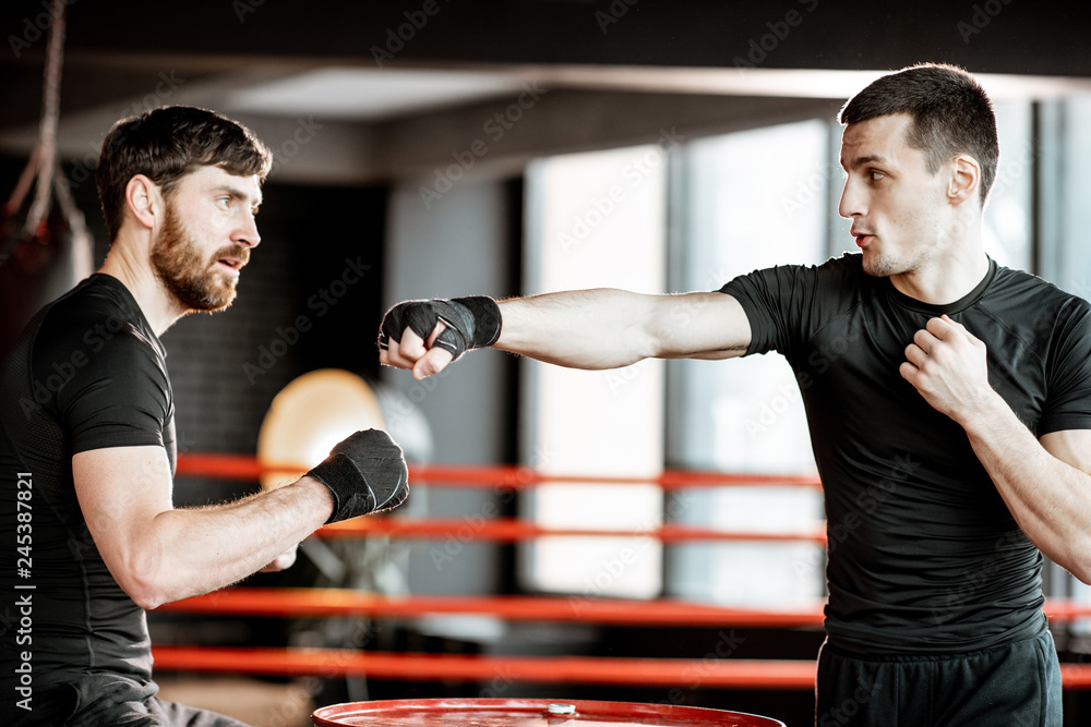 Boxing Rin Training Boxing trainer showing to a man how to fight, teaching to box in the ...