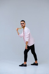 fashionable sophisticated man in a pink jacket and black trousers, wears a gold chain, the expression of emotions gestures with his hands