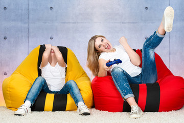  Mother and son sit on chairs bags and play video games .Emotions.