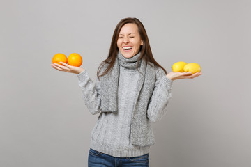 Wall Mural - Laughing young woman in gray sweater, scarf with closed eyes hold lemons oranges isolated on grey background. Healthy fashion lifestyle people sincere emotions cold season concept. Mock up copy space.