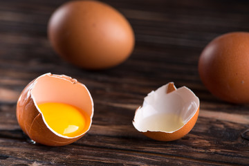 Wall Mural - Fresh brown eggs on rustic table. Broken egg with yolk.