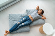 © Maridav - Home lifestyle happy Asian woman relax lying down on living room floor pillows relaxing contemplative looking at windows. New condo apartment satisfaction homeowner young girl enjoying house.