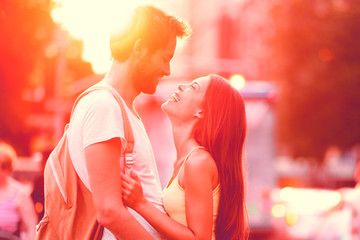 Couple in love laughing hugging looking at each other in sunset. People falling in love, happiness fun. Interracial young couple embrace on date. Caucasian man Asian woman on city street lifestyle.