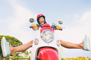 Wall Mural - Travel fun funny tourist carefree driving scooter on summer road trip. Screaming Asian girl goofing around with legs up riding motorcycle.