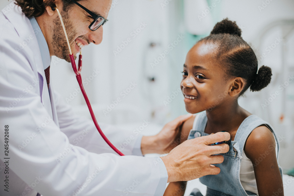 Friendly pediatrician checking a little girls heart - obrazy, fototapety, plakaty 