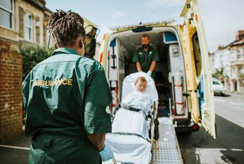 Wall Mural - Paramedics moving a young patient on a stretcher into an ambulance